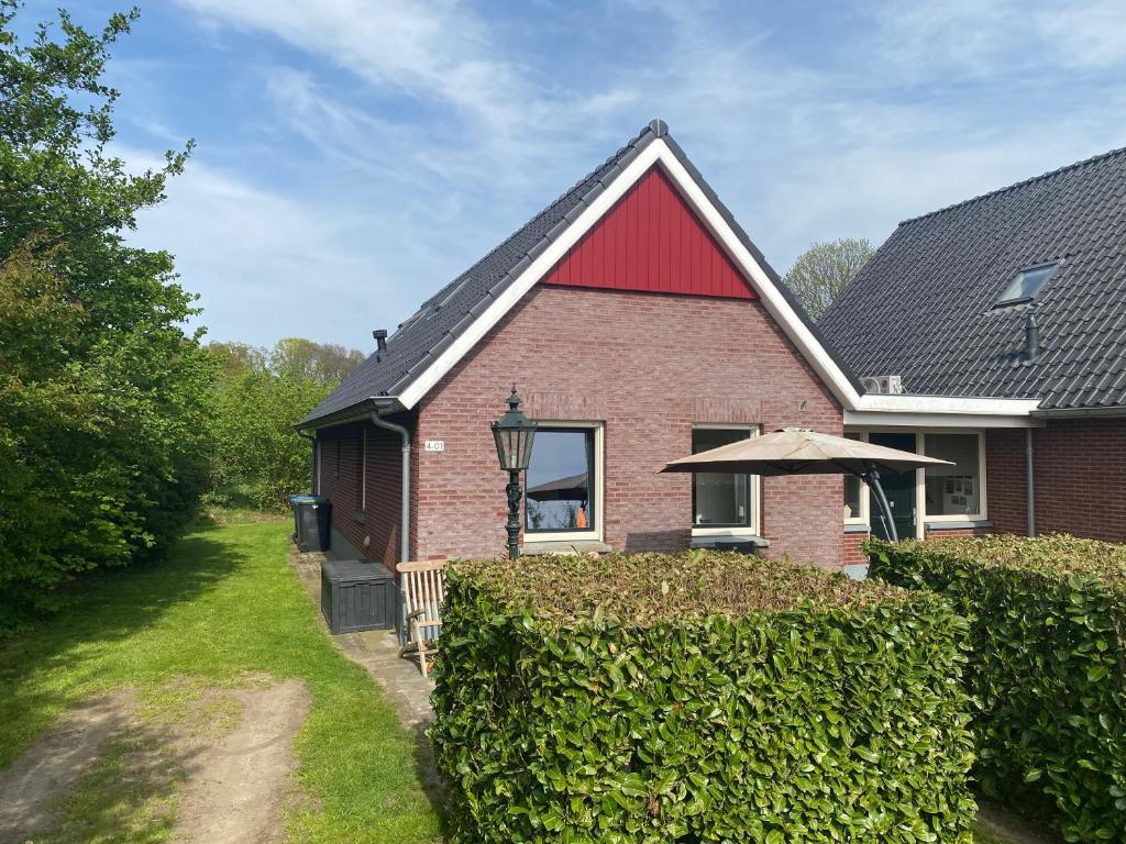 a red brick house with an umbrella over a hedge at De Daalse Oase in Aalten