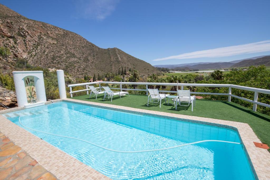 einem Pool mit Stühlen und einem Berg im Hintergrund in der Unterkunft Montagu Little Sanctuary - Hot Spring Access at reduced price in Montagu