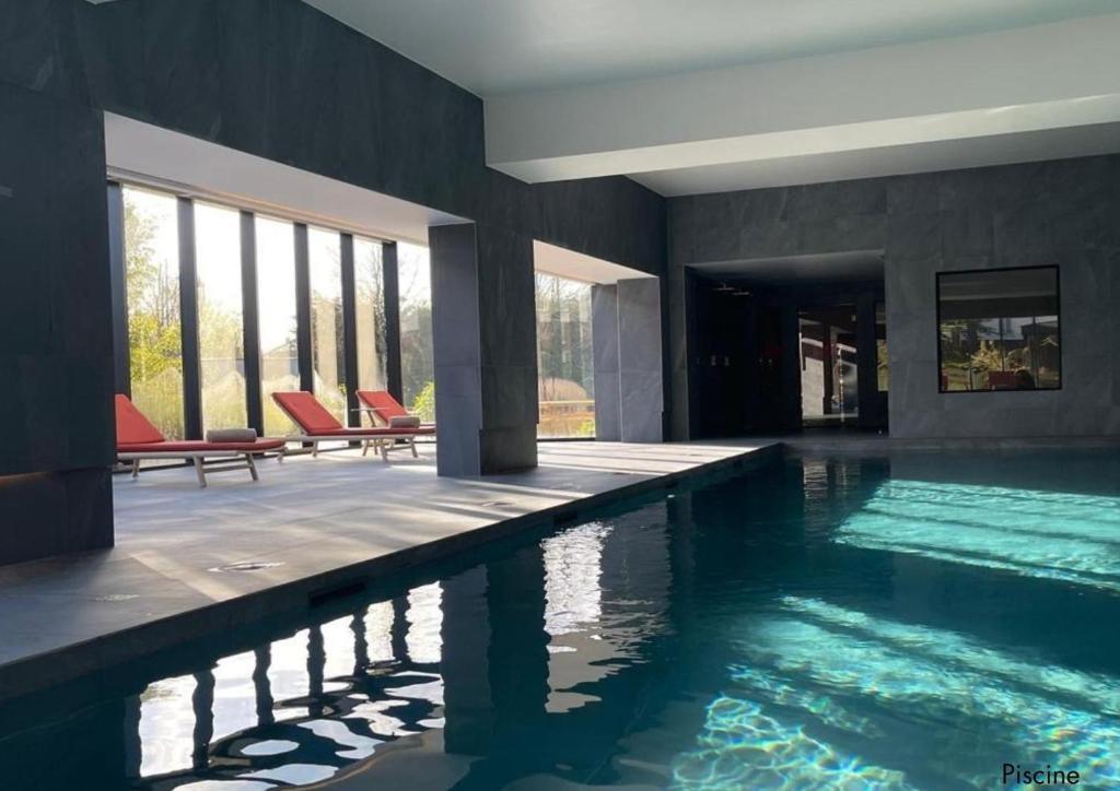 uma piscina com cadeiras vermelhas numa casa em Paxton Paris MLV em Ferrières-en-Brie