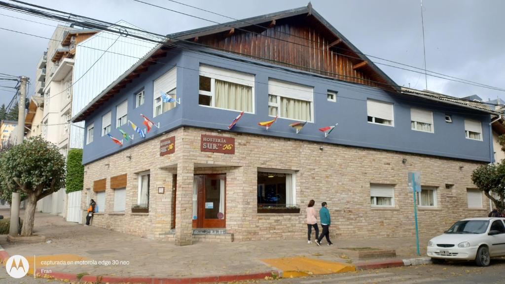 a building with people standing in front of it at Hostería Sur in San Carlos de Bariloche