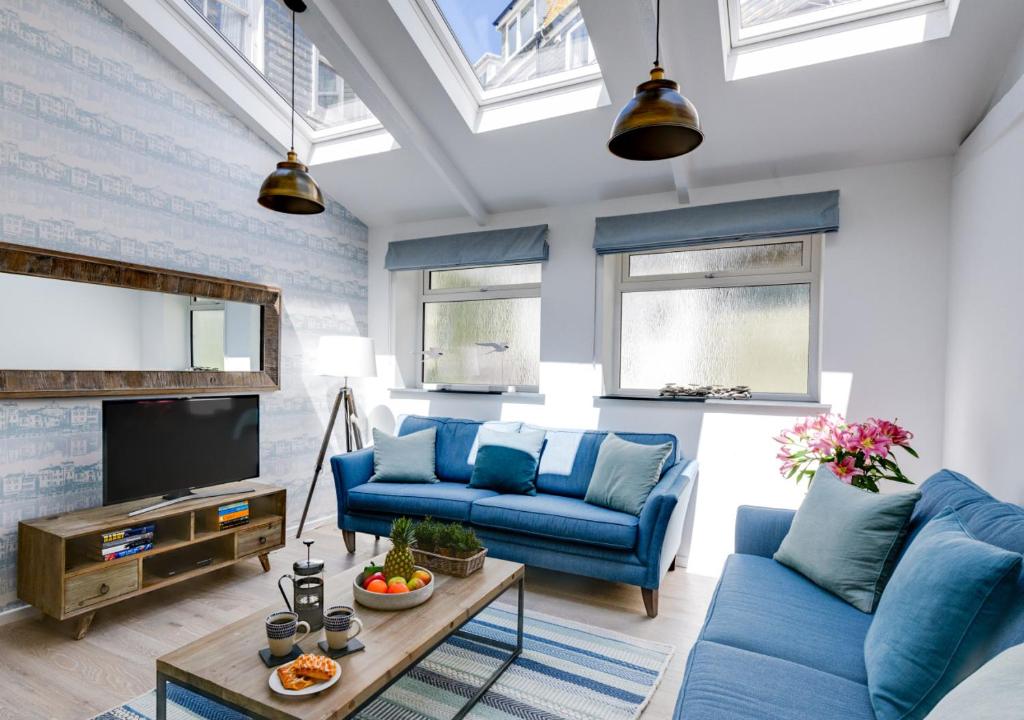 a living room with blue couches and a tv at Sail Loft Studio in St Ives