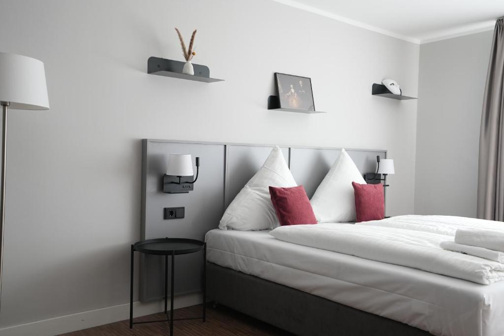 1 dormitorio con 1 cama blanca grande con almohadas rojas en Boutique Kaiser - Hotel & Apartments, en Frankfurt