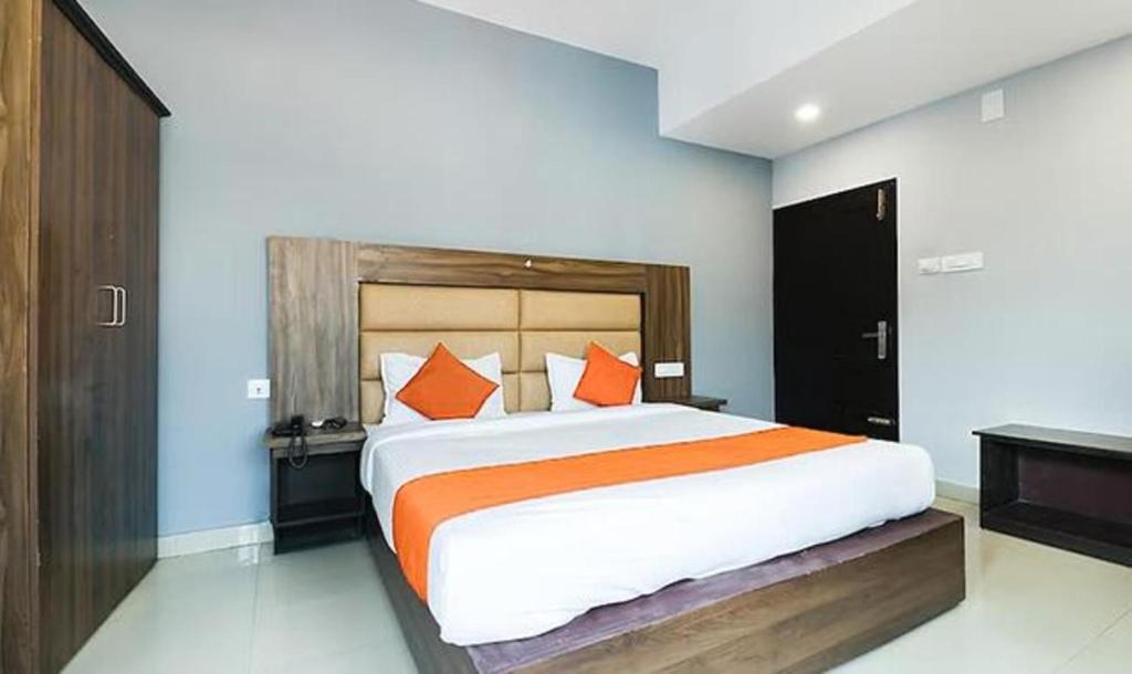 a bedroom with a large bed with orange pillows at Queens Residency - Kochi in Ernakulam