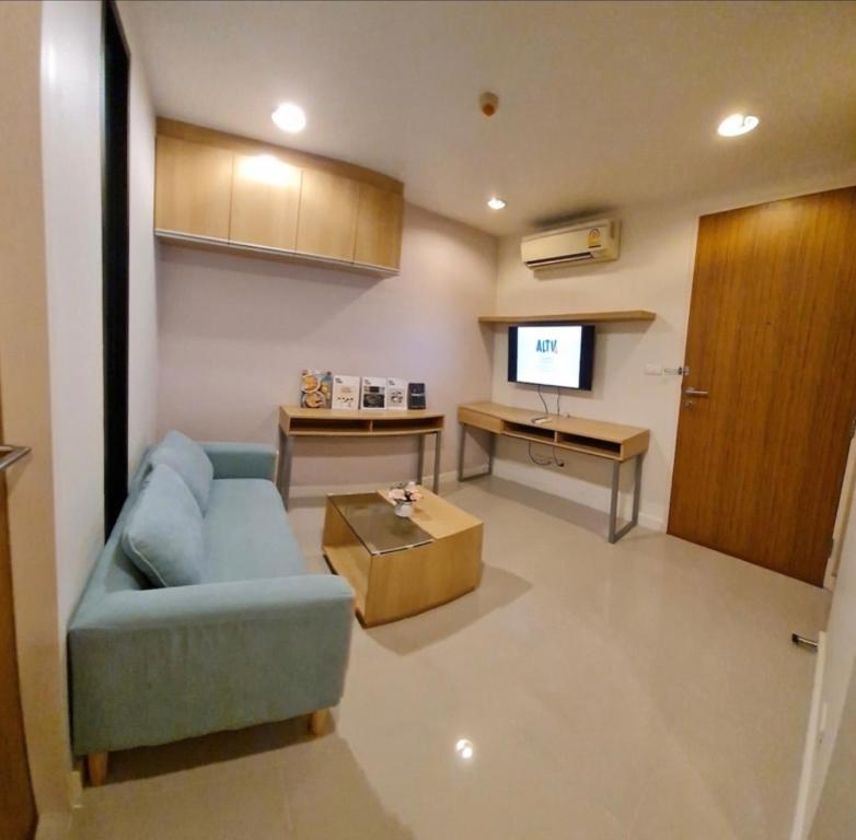 uma sala de estar com um sofá azul e uma televisão em Free Airport Pick up ,1 BR 4 mins from BTS Ekkamai em Klong Toi