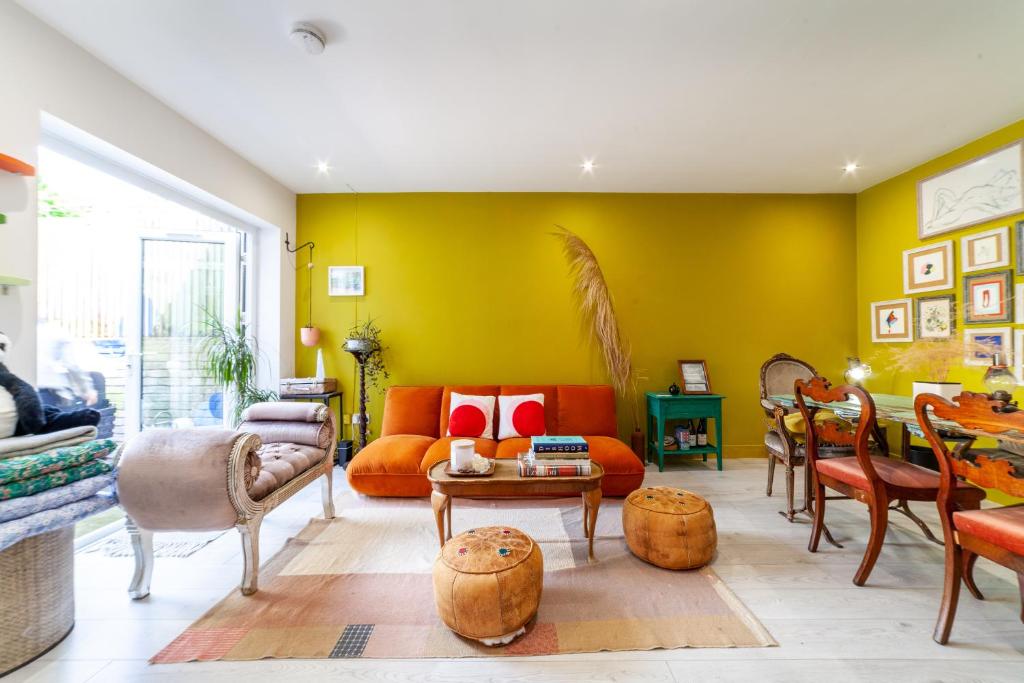 a living room with yellow walls and an orange couch at Unique bungalow nearby the iconic Alexandra Palace in London