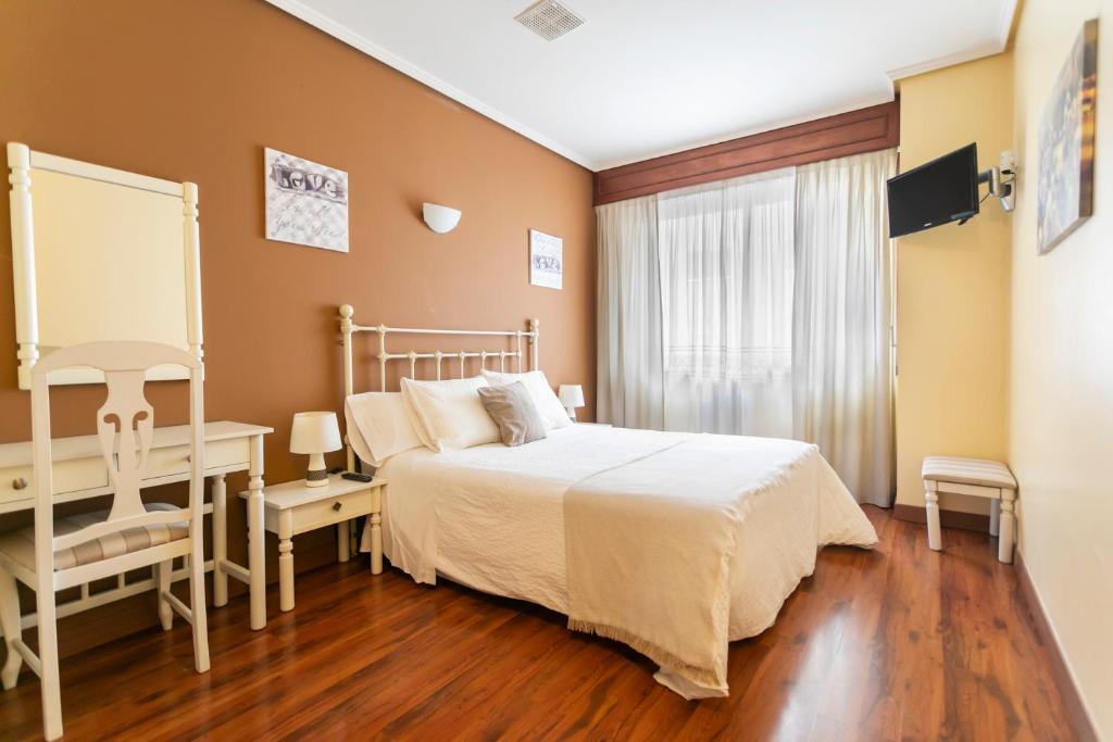 a bedroom with a bed and a desk and a window at Hotel América Ferrol in Ferrol