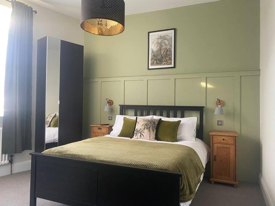 a bedroom with a large bed with green walls at 55 High Street in Hastings