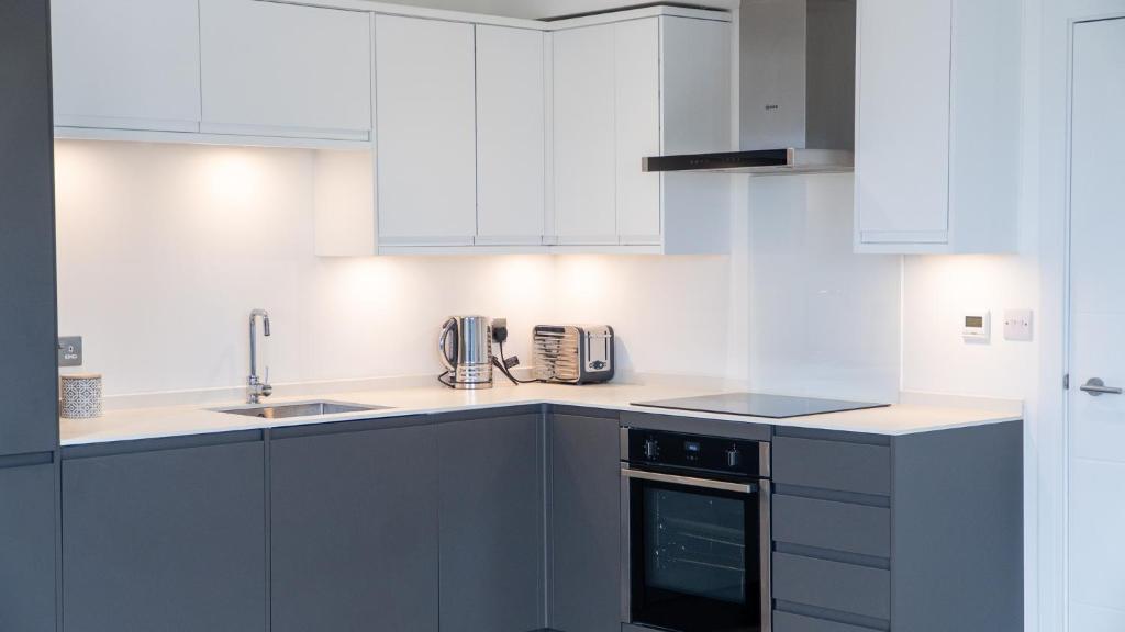 a kitchen with white cabinets and a sink at Lovely 2 bed Penthouse in Loughton central location in Loughton