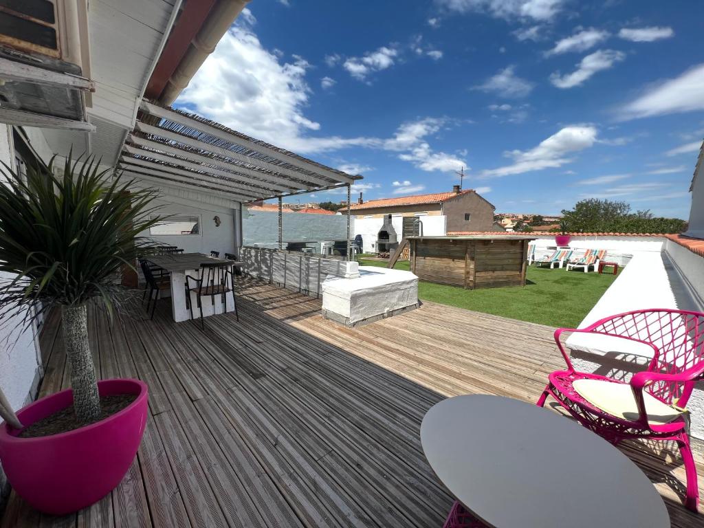 une terrasse en bois avec des chaises et une plante en pot dans l'établissement Grand appartement avec terrasse et piscine privée, à Saint Pierre La Mer