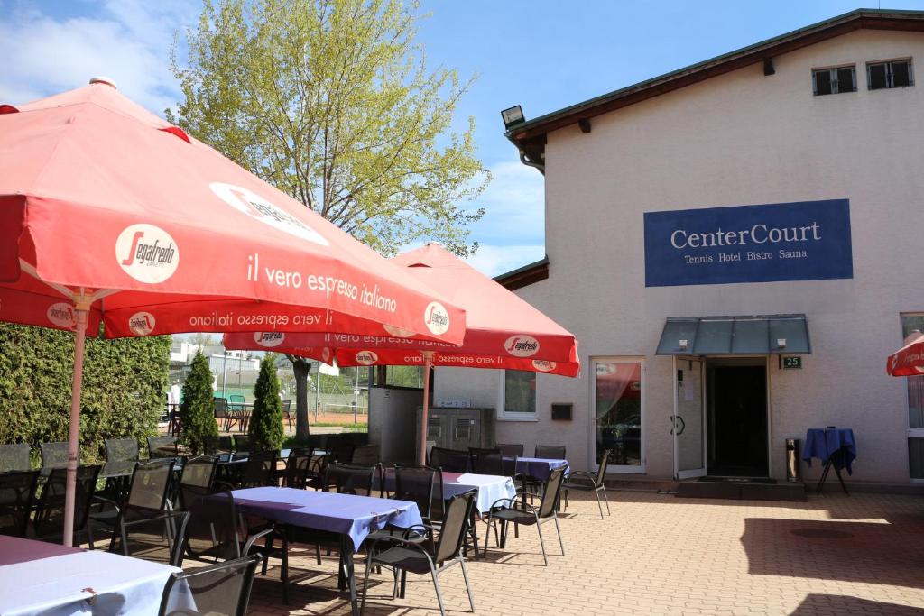 ein Restaurant mit Tischen und Sonnenschirmen vor einem Gebäude in der Unterkunft CenterCourt Hotel in Graz