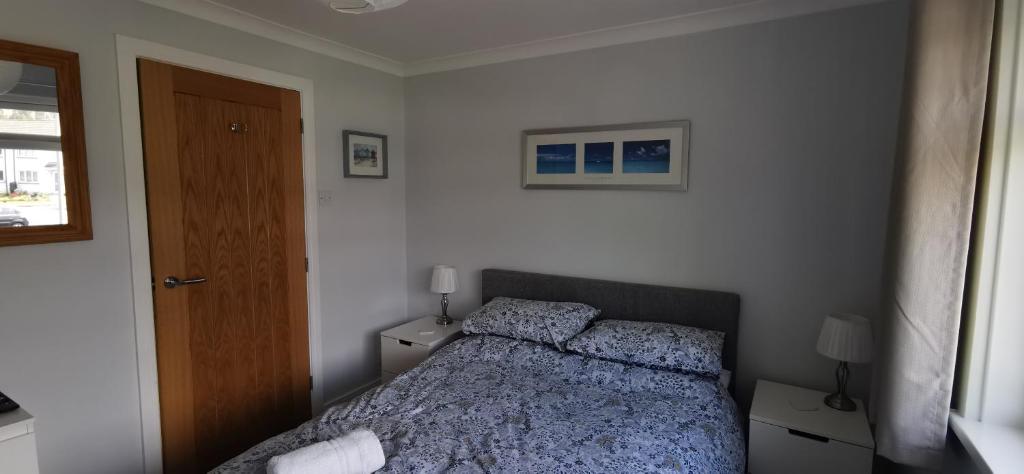 a bedroom with a bed and two night stands and a door at Chy Lowen - Private rooms, not en-suite, in private home with cats, close to Eden & beaches in Saint Blazey