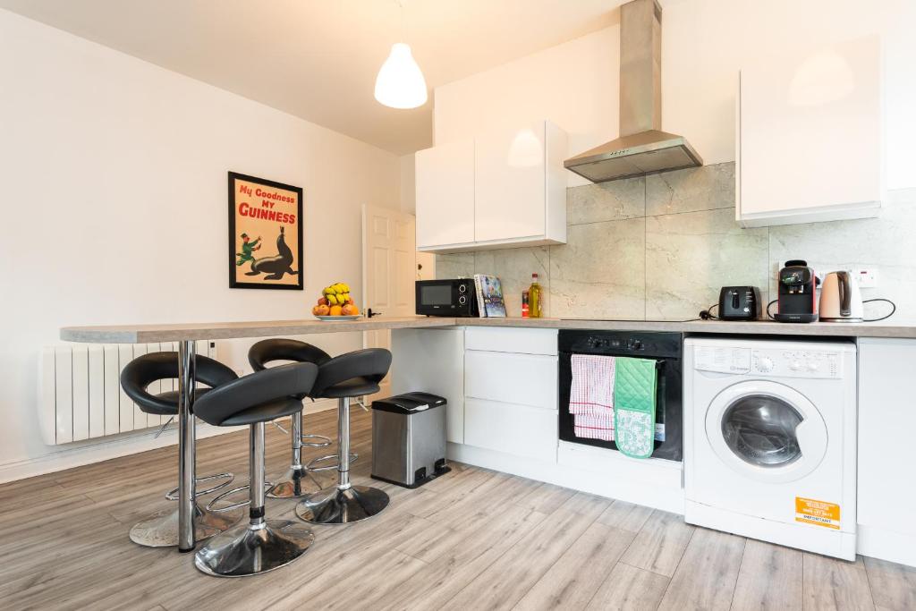 eine Küche mit einem Tisch, einer Waschmaschine und einem Trockner in der Unterkunft Central Dublin Apartment Near Guinness & Heuston Station in Dublin