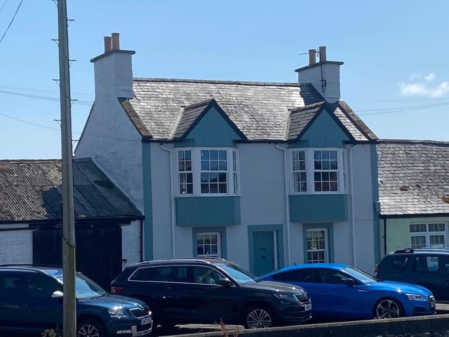 a blue and white house with parked cars in front at 3 bedroom townhouse right on the harbour in Isle of Whithorn