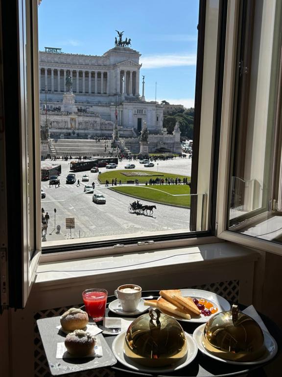 a table with plates of food in front of a window at Piazza Venezia Luxury Suite in Rome