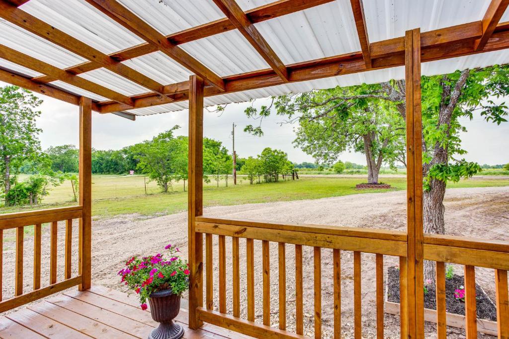 un porche de madera con pérgola y flores en Northeast Texas Vacation Rental about 6 Mi to Commerce, en Commerce