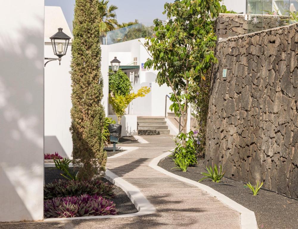 a walkway with a stone wall and a street at ILUNION Costa Sal Lanzarote in Puerto del Carmen