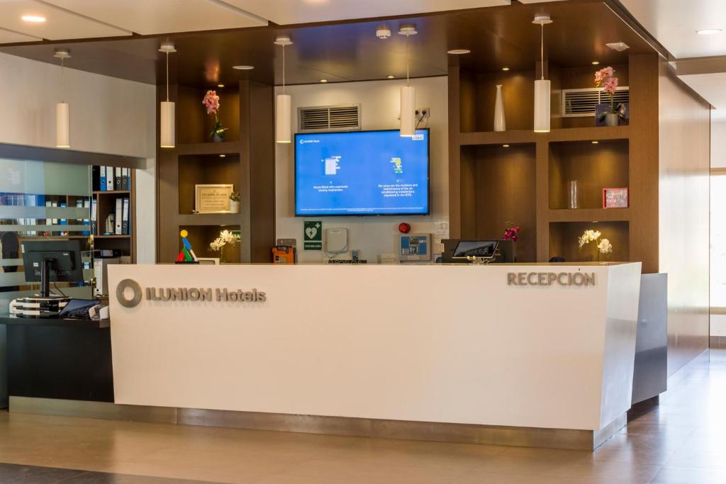 a lobby of a library with a reception desk and a tv at ILUNION Costa Sal Lanzarote in Puerto del Carmen
