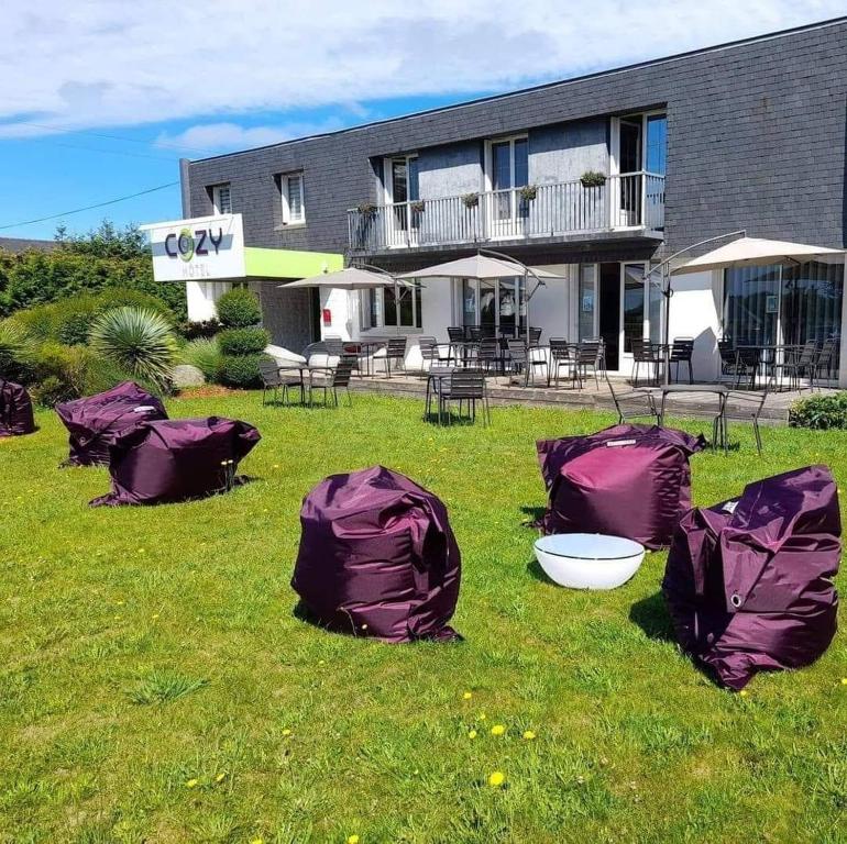 un groupe de tentes violettes dans l'herbe devant un bâtiment dans l'établissement Cozy Hôtel Logis Morlaix, à Plouigneau