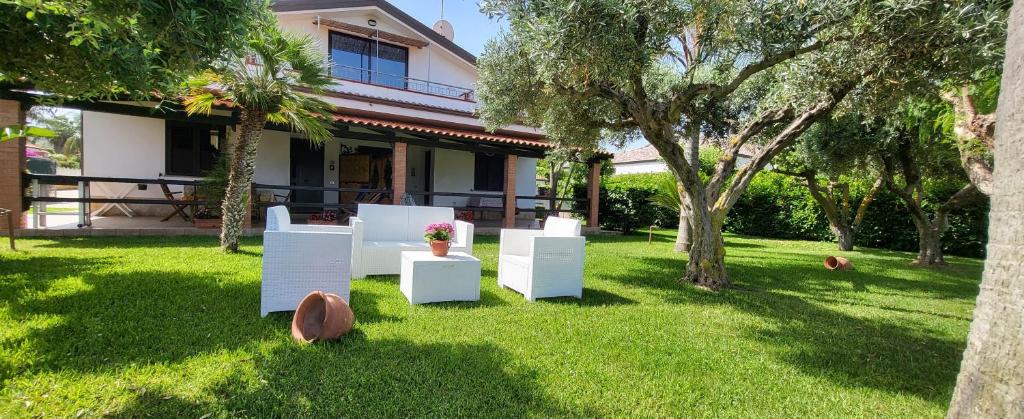 a yard with white furniture in front of a house at Villa Ilaria casa vacanza Capo Vaticano - Tropea in Capo Vaticano