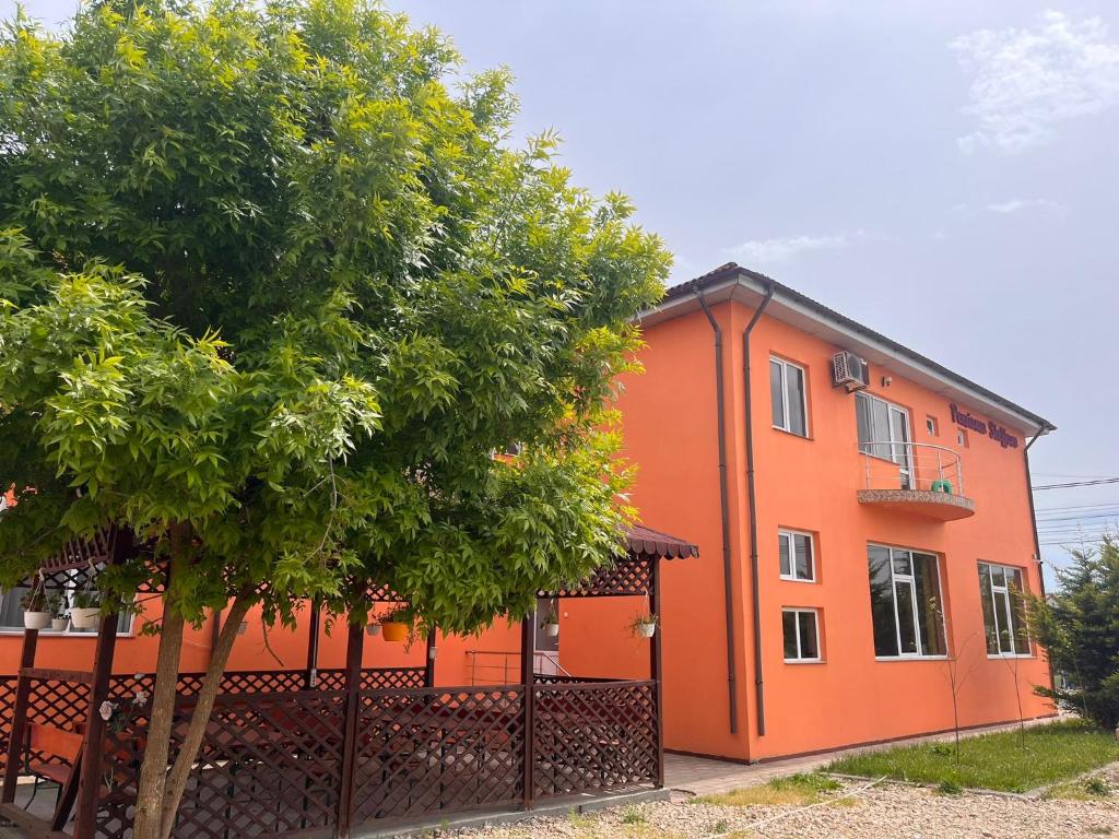 un edificio naranja con un árbol delante de él en Steffano Costinesti, en Costinesti