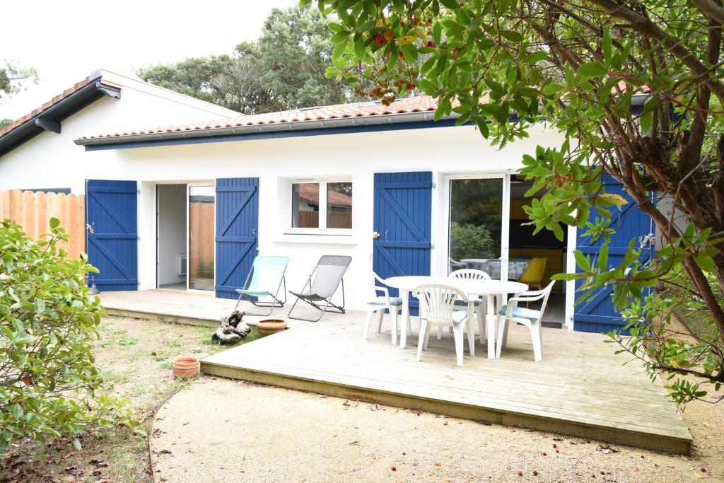 une maison bleue et blanche avec une table et des chaises dans l'établissement Maisonnette - Hossegor agréable maisonnette entre lac et océan, à Soorts-Hossegor