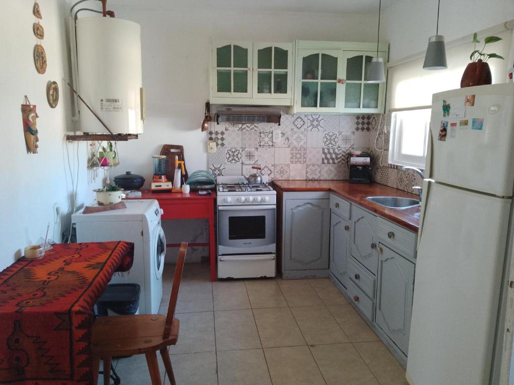 una cocina con electrodomésticos blancos y una mesa. en Como en casa en Gualeguaychú