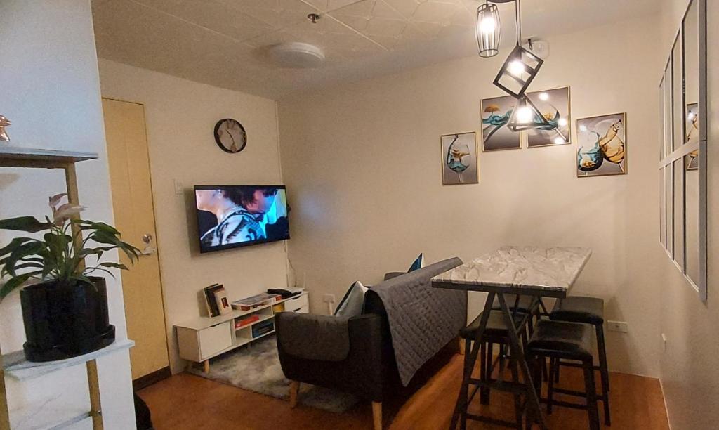a living room with a table and a tv on the wall at Davao Vacation Hub near Sasa ferry terminal with netflix,Wifi, pool access in Davao City