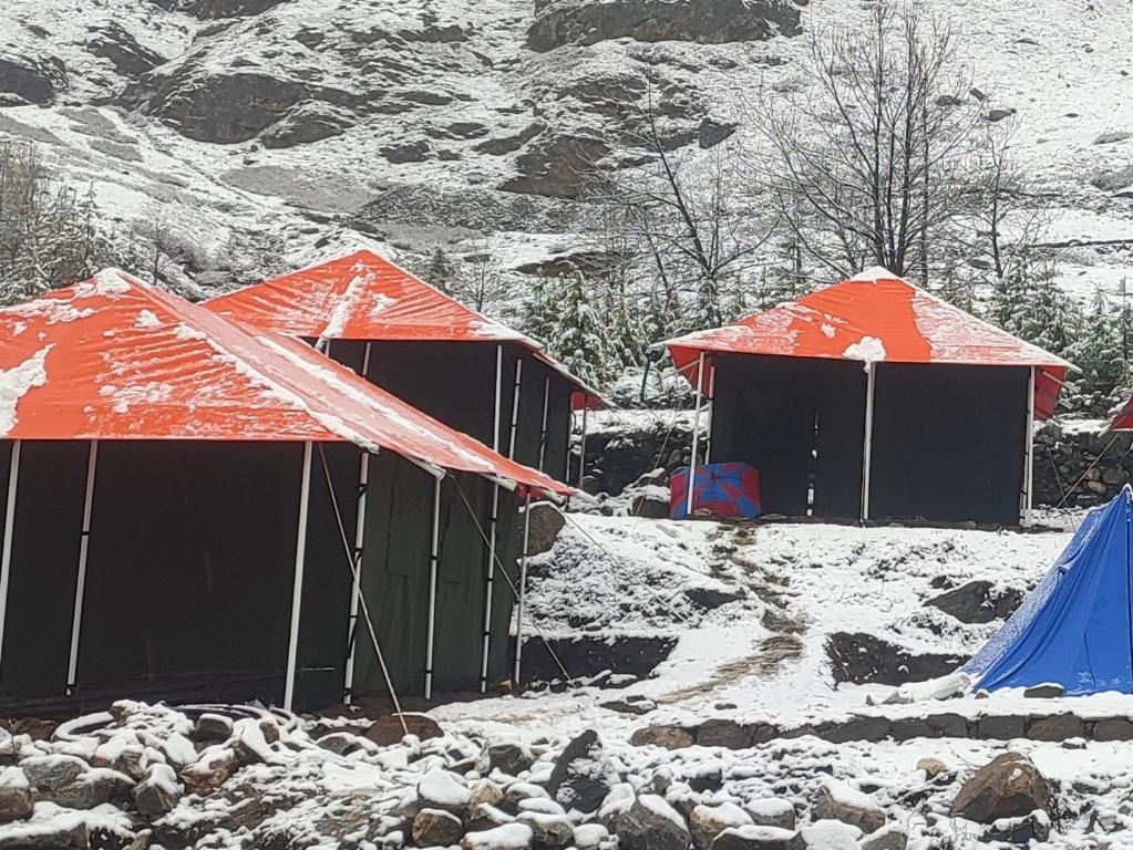 twee hutten met oranje daken in de sneeuw bij Buddy Hikers Stay Badrinath in Badrīnāth
