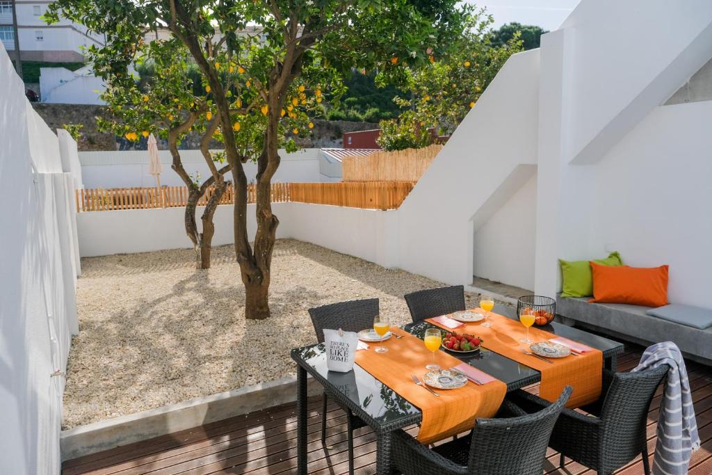 een patio met een tafel en stoelen en een boom bij Cozy & Bright Lisbon-O campo na cidade in Lissabon