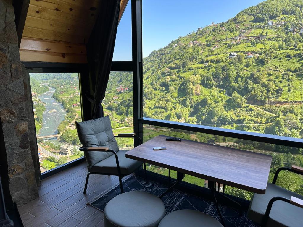 a table and chairs in a room with a view of a mountain at Soore Bungalov in Ardeşen