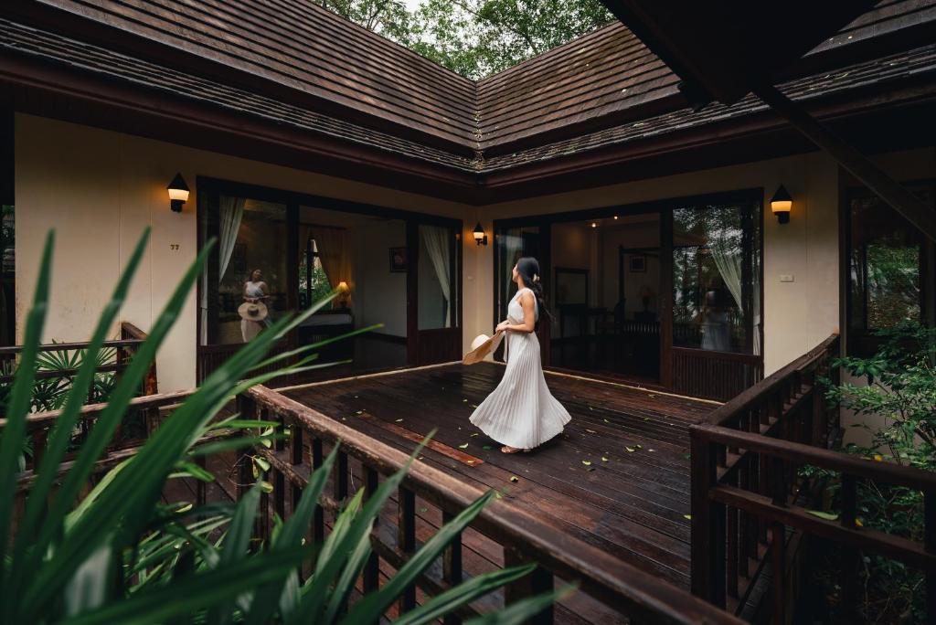 Eine Frau in einem Hochzeitskleid, die auf einer Holzterrasse wandelt. in der Unterkunft Kooncharaburi Resort - Koh Chang in Ko Chang