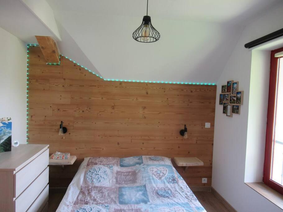 a bedroom with a bed with a wooden wall at Location appartement T2 38 m2 2 chambres in Allevard