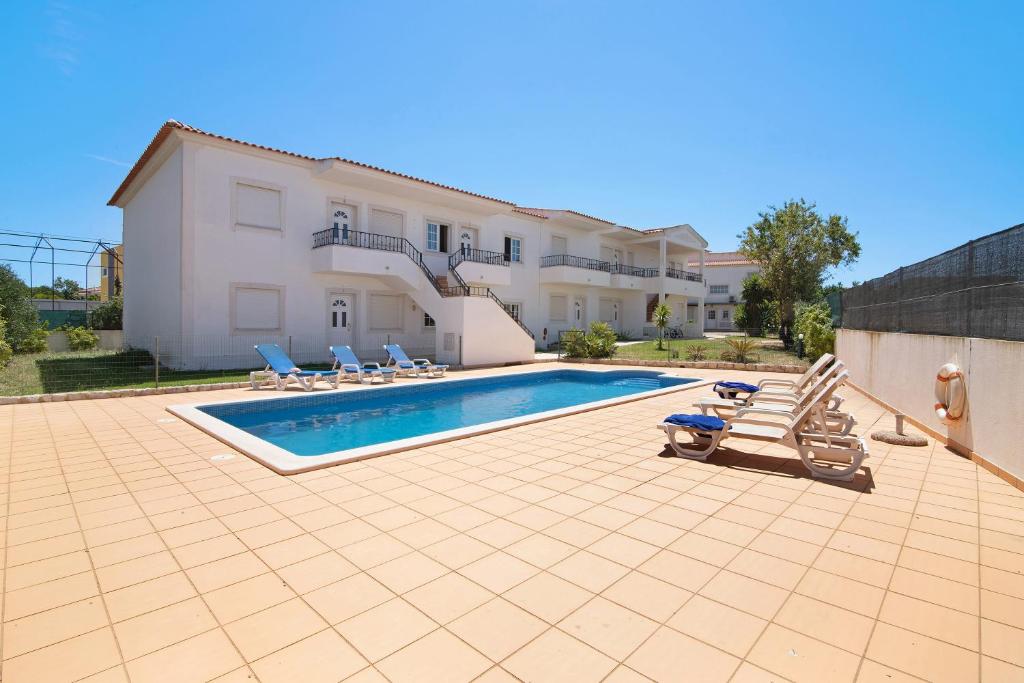 a swimming pool in front of a house at Algarve apartments L in Olhos de Água