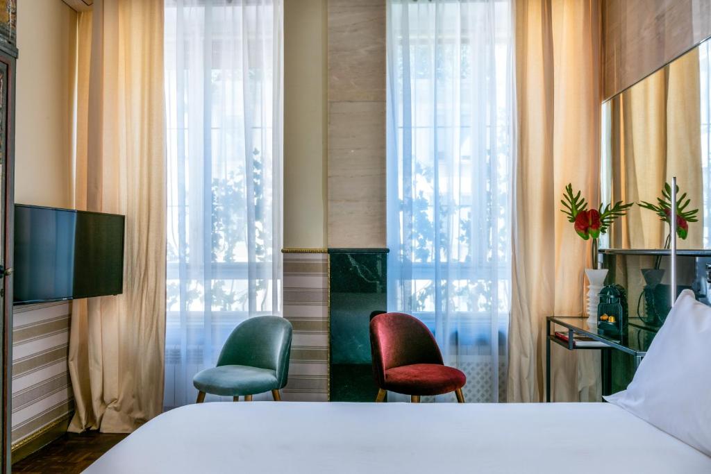 ein Hotelzimmer mit einem Bett und zwei Stühlen in der Unterkunft Rivière Private Rooms Alla Scala in Mailand