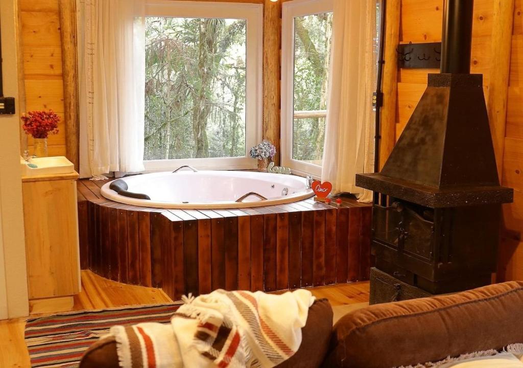 a bath tub in a room with a window at Cabana hidromassagem Morada Alma Gêmea in Bateias de Baixo