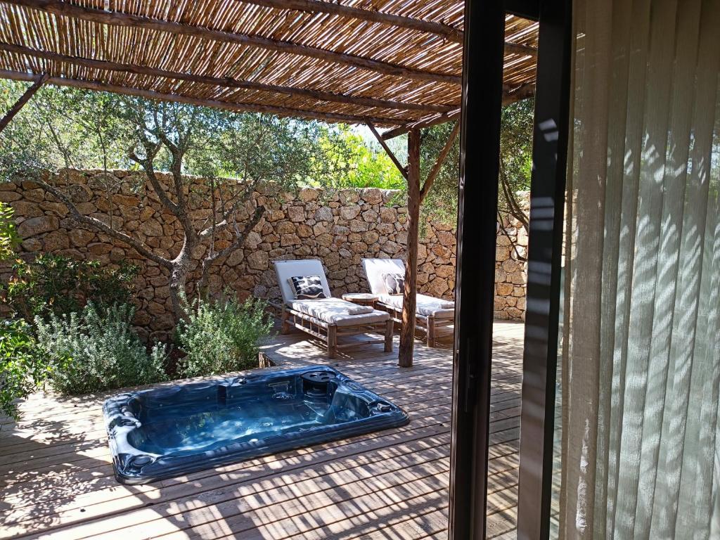 een hot tub op een patio met een stoel bij Hôtel Les Suites Du Maquis in Bonifacio
