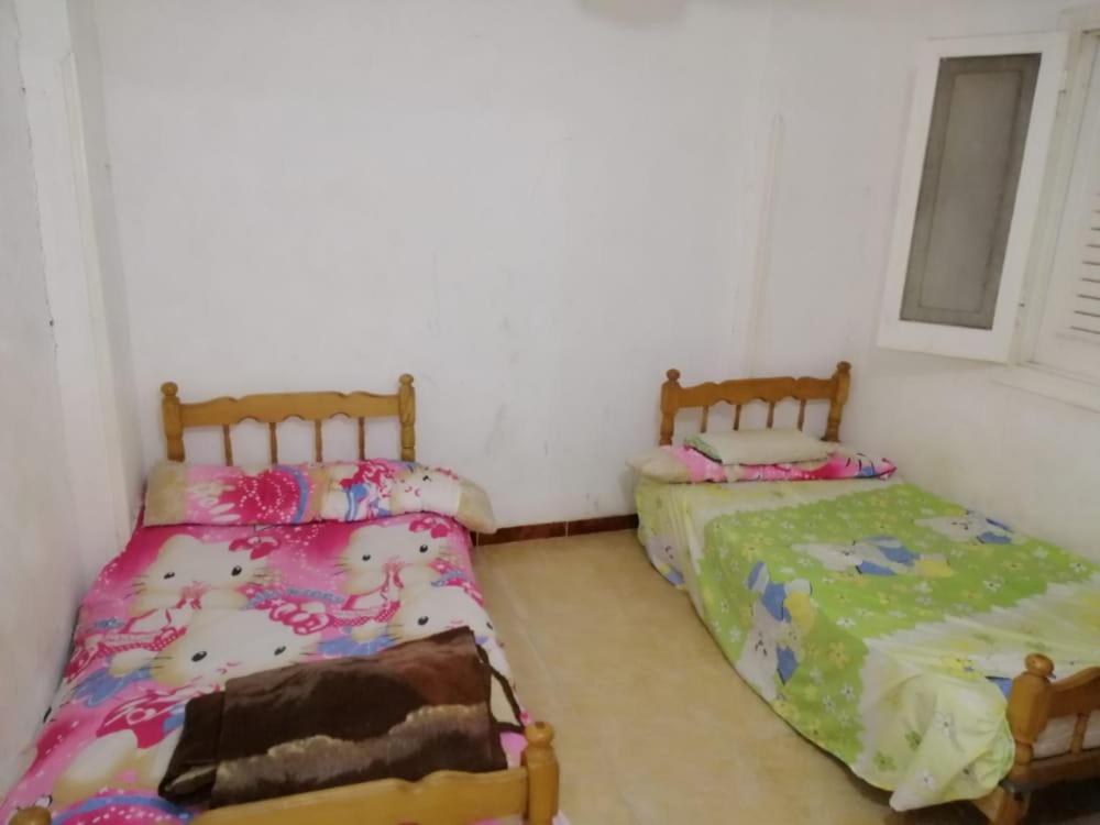 1 Schlafzimmer mit 2 Betten und einem Fenster in der Unterkunft شقة مصيفية العجمى in Alexandria
