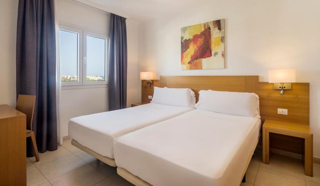 a bedroom with a large white bed and two windows at ILUNION Costa Sal Lanzarote in Puerto del Carmen