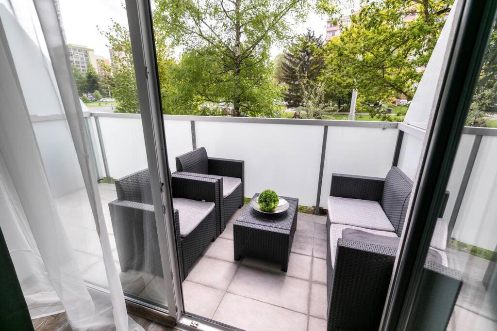 a balcony with two chairs and a table with a plant at ALURE RESIDENCES 1 & 24h self check-in, free parking in front of the apartment building, new building, terrace, cafe with breakfast in the apartment building, next to the aqua park in Banská Bystrica
