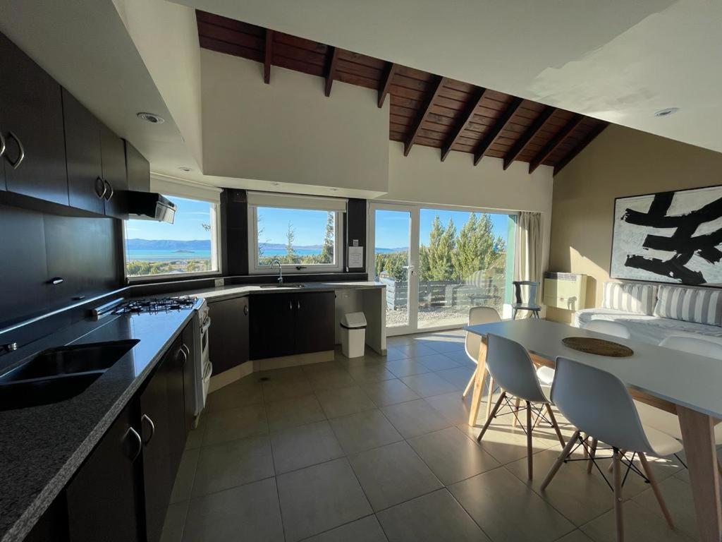 a kitchen with a table and chairs and some windows at MI CASA TU CASA in El Calafate