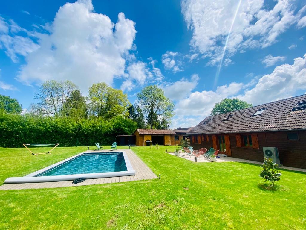 une cour avec une piscine et une maison dans l'établissement Charmante maison avec Piscine chauffée à 1h30 de Paris - Perche, à Les Autels-Villevillon