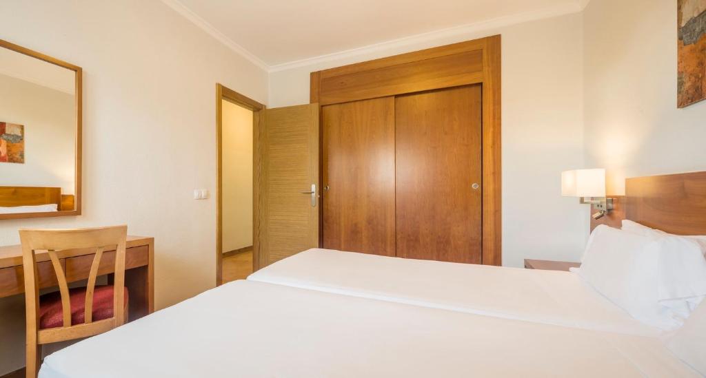 a hotel room with a large white bed and a desk at ILUNION Costa Sal Lanzarote in Puerto del Carmen