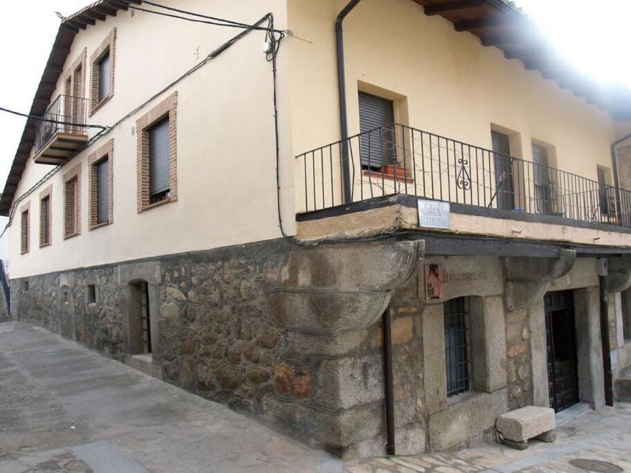 um edifício antigo com uma varanda ao lado em El Elaboratorio - casa Rural del siglo XVIII con piscina em Villarejo del Valle