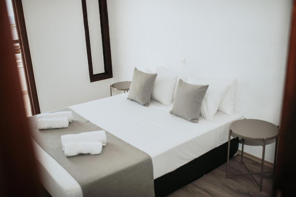 uma cama branca com almofadas brancas e um banco em Ovis Hotel Apartments em Agia Napa