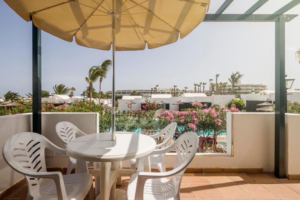 a white table and chairs and an umbrella on a balcony at ILUNION Costa Sal Lanzarote in Puerto del Carmen