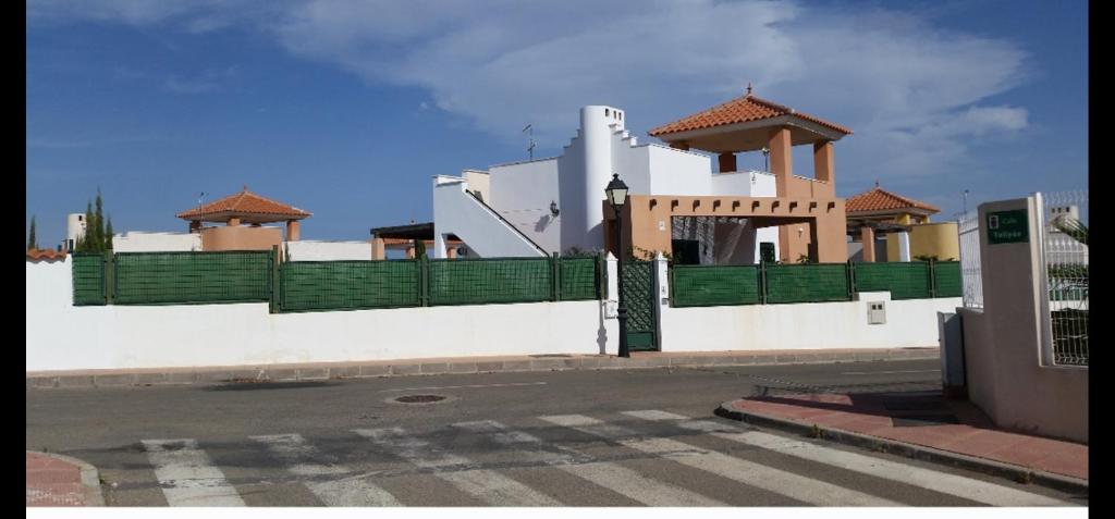 a white building with a green fence next to a street at Stunning 3-Bed Villa detached with private pool in Zurgena