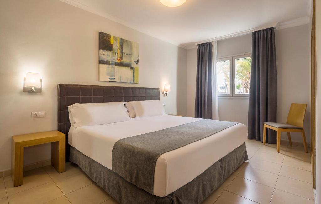 a bedroom with a large bed and a chair at ILUNION Costa Sal Lanzarote in Puerto del Carmen
