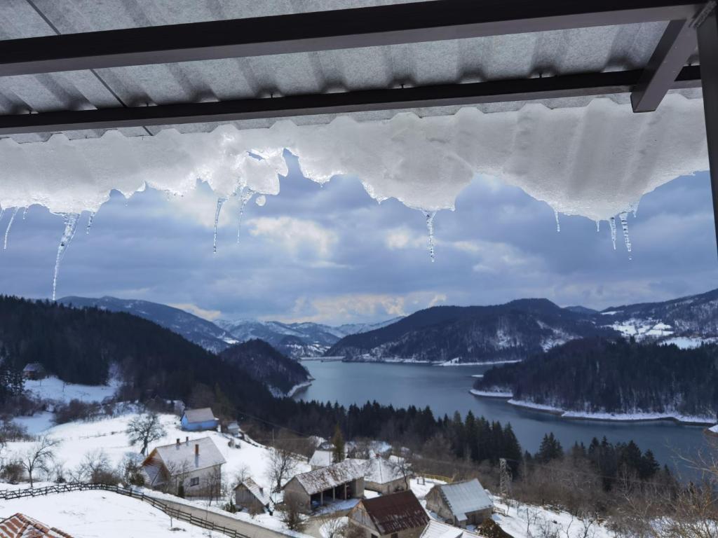 a window with icicles hanging from it with a view of a lake at Villa Montana Zaovine in Bajina Bašta