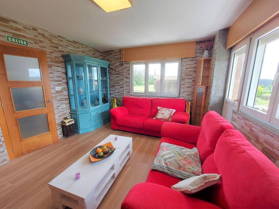 a living room with a red couch and a table at Casa Dabuela INCostadaMorte in Muxia
