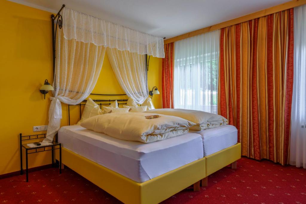 a bedroom with a large bed with yellow walls at Gasthof Waldwirt in Russbach am Pass Gschütt
